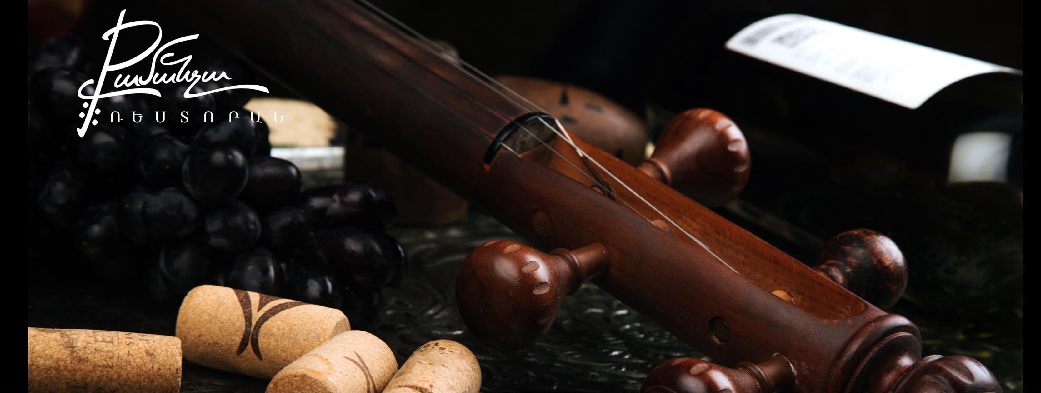 A kamancha neck resting beside black grapes and wine corks in candlelight
