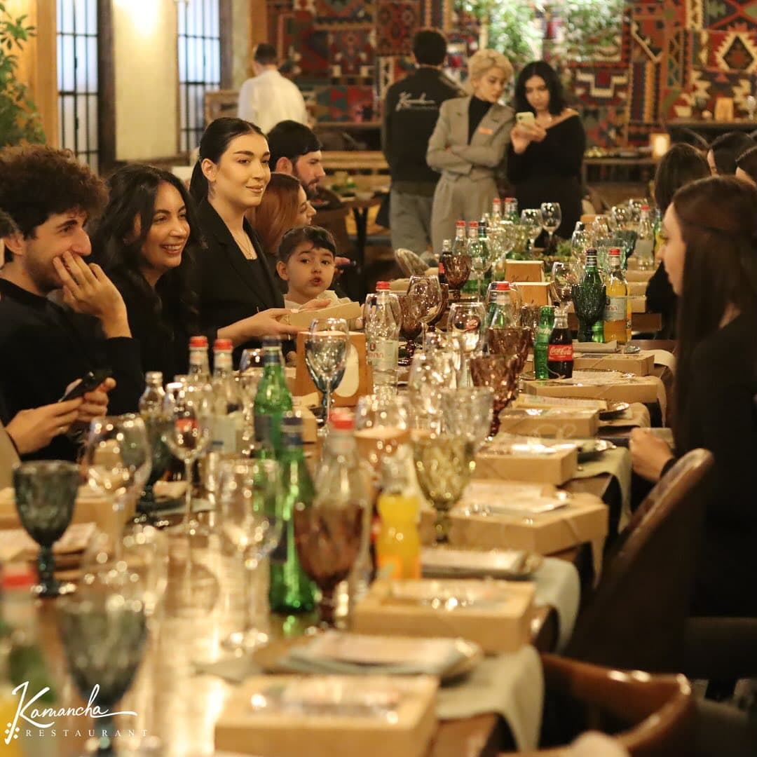 A full, festive table of guests at Kamancha